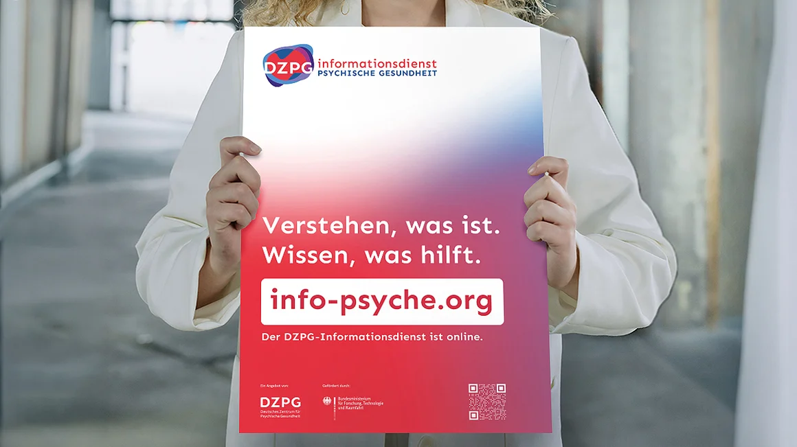 Eine Frau hält ein Werbeplakat für den Informationsdienst Psychische Gesundheit des Deutschen Zentrums für Psychische Gesundheit in die Kamera