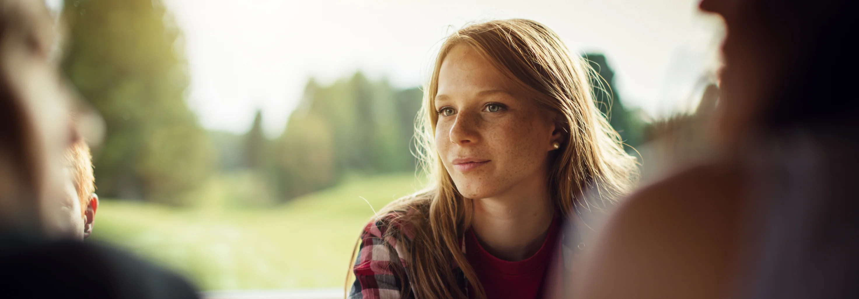Junge Frau spricht mit anderen Personen, die an einem Tisch sitzen