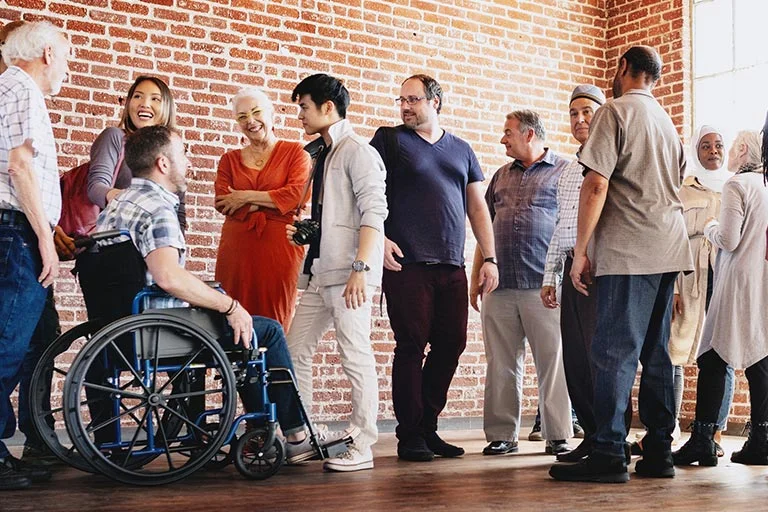 Gruppe von Menschen im Gespräch, ein Mann sitzt im Rollstuhl