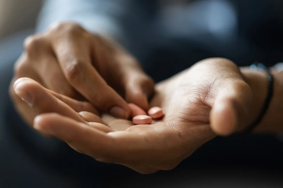 Nahaufnahme eines Mannes, der mehrere Tabletten in der Hand hält